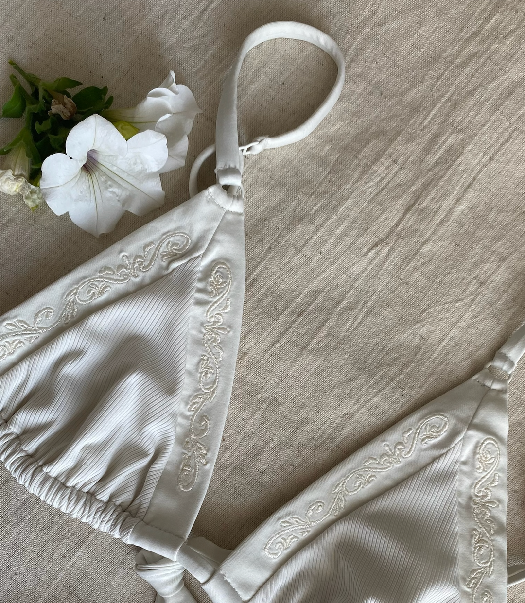Close up of the rib fabric and embroidery details on the cup of the triangle bikini top in ivory white